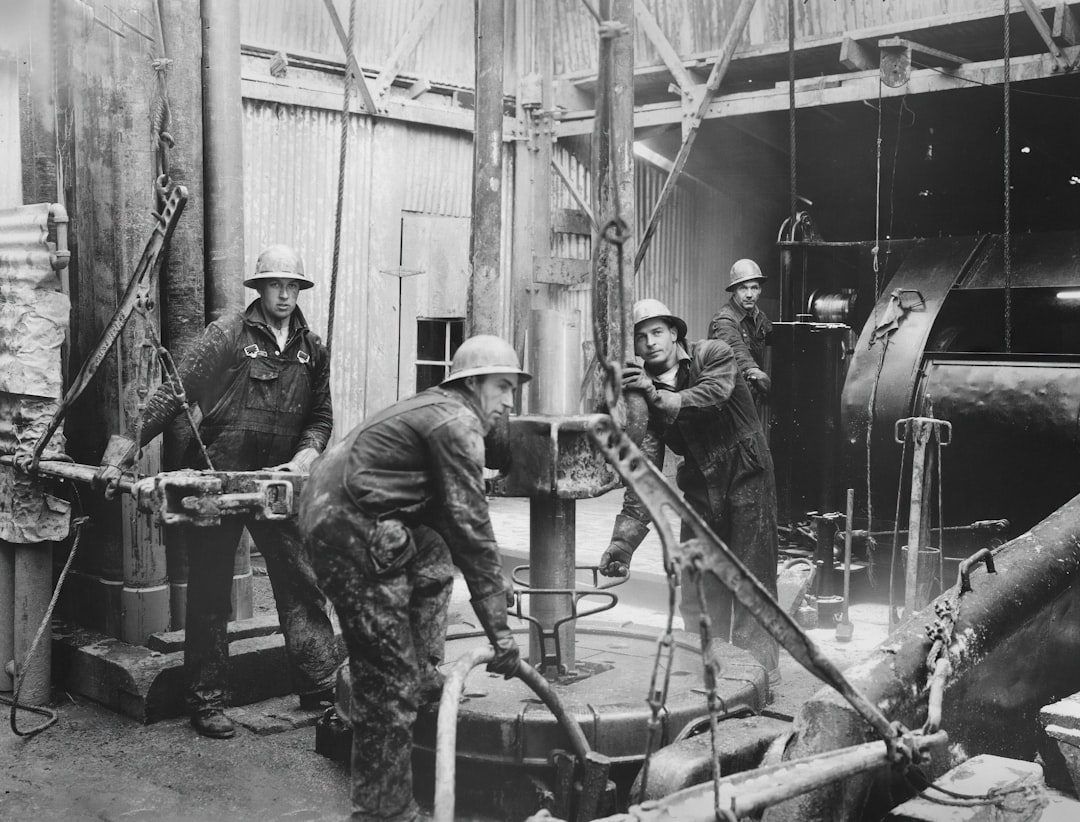 a black and white photo of men working in a factory