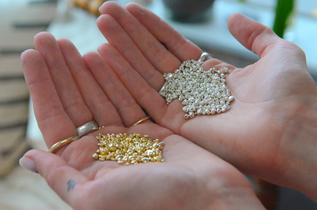Hands holding gold nuggets and silver jewelry