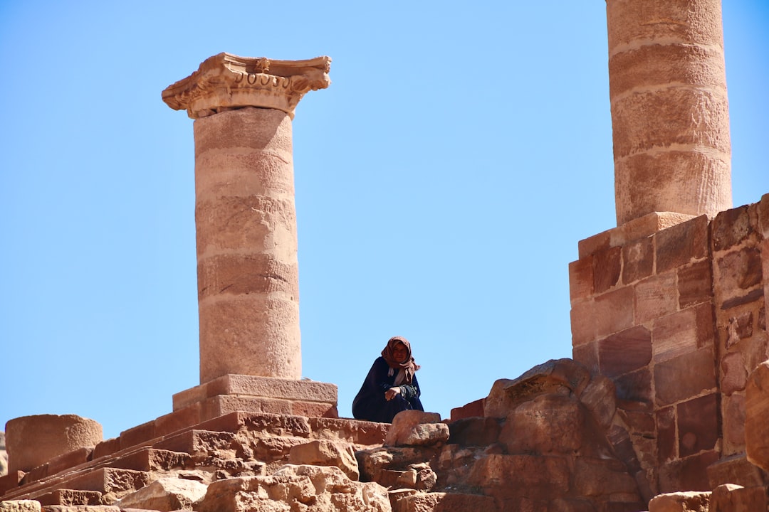 man in black jacket sitting on brown concrete tower during daytime