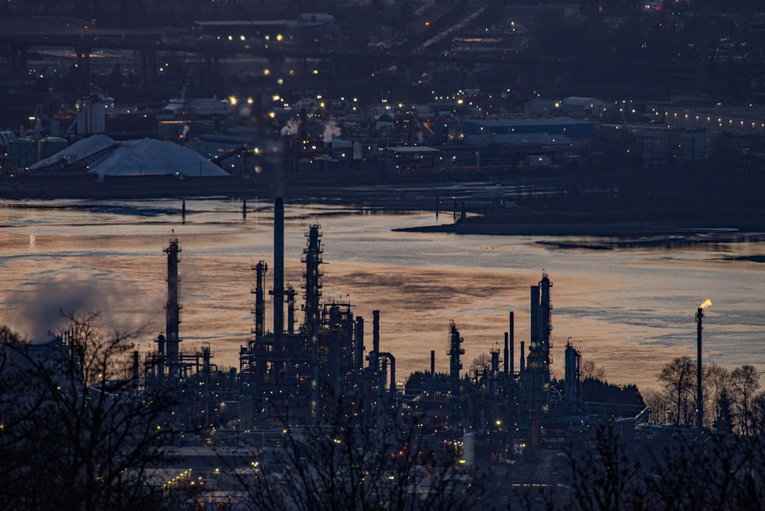 Oil refinery by a river at dusk.