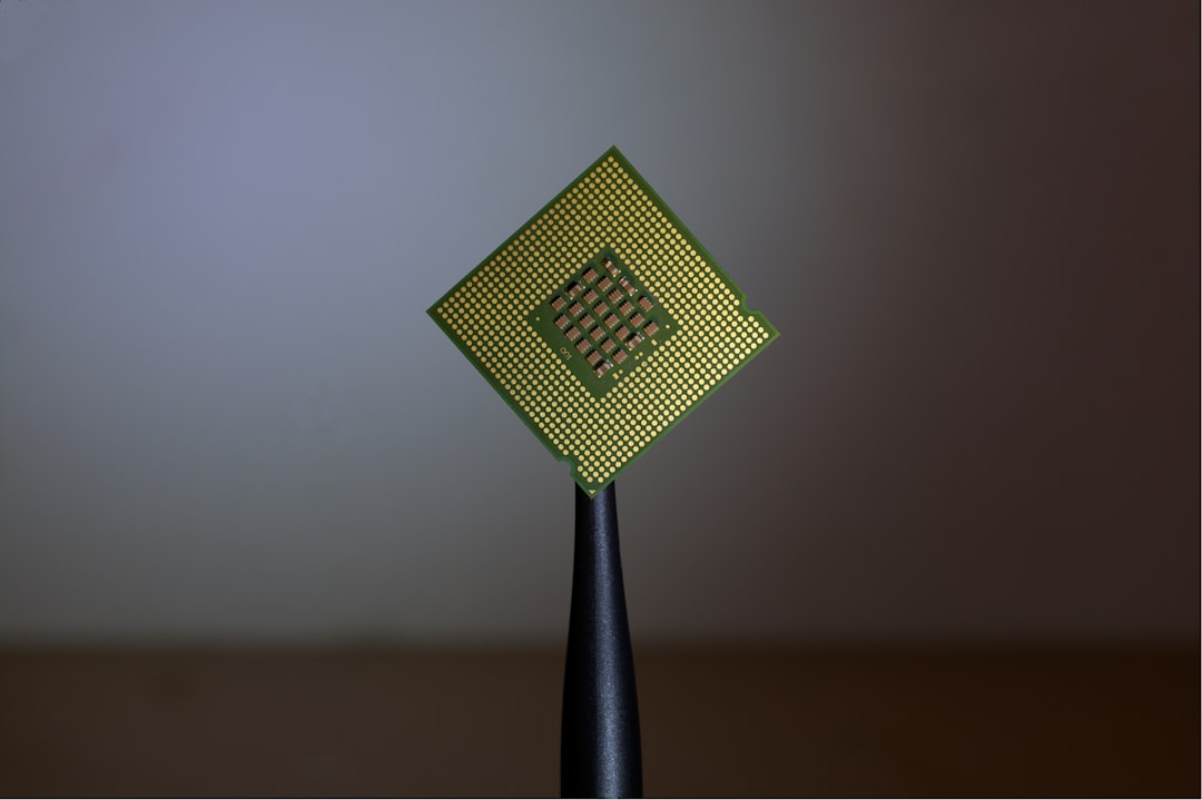 A computer processor held by black tweezers against a neutral background