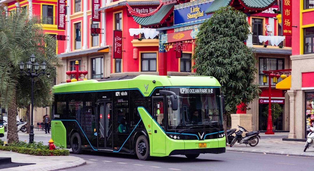 A bright green electric bus drives down a street.