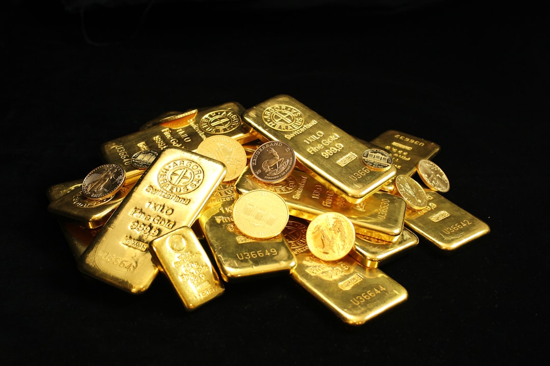 A pile of gold bars and coins on a black background