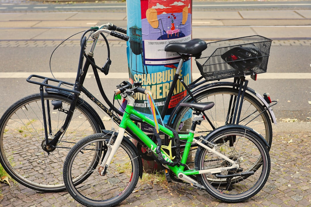 Two bicycles locked to a pole on sidewalk.