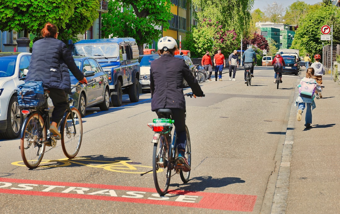 People cycling on a city street with cars.