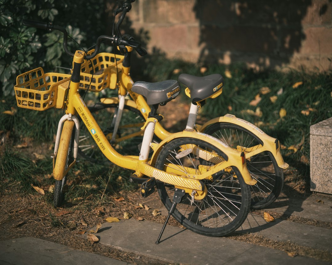 Two yellow bicycles parked outdoors near grass