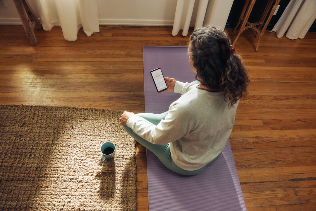 Woman meditating on yoga mat with phone and drink