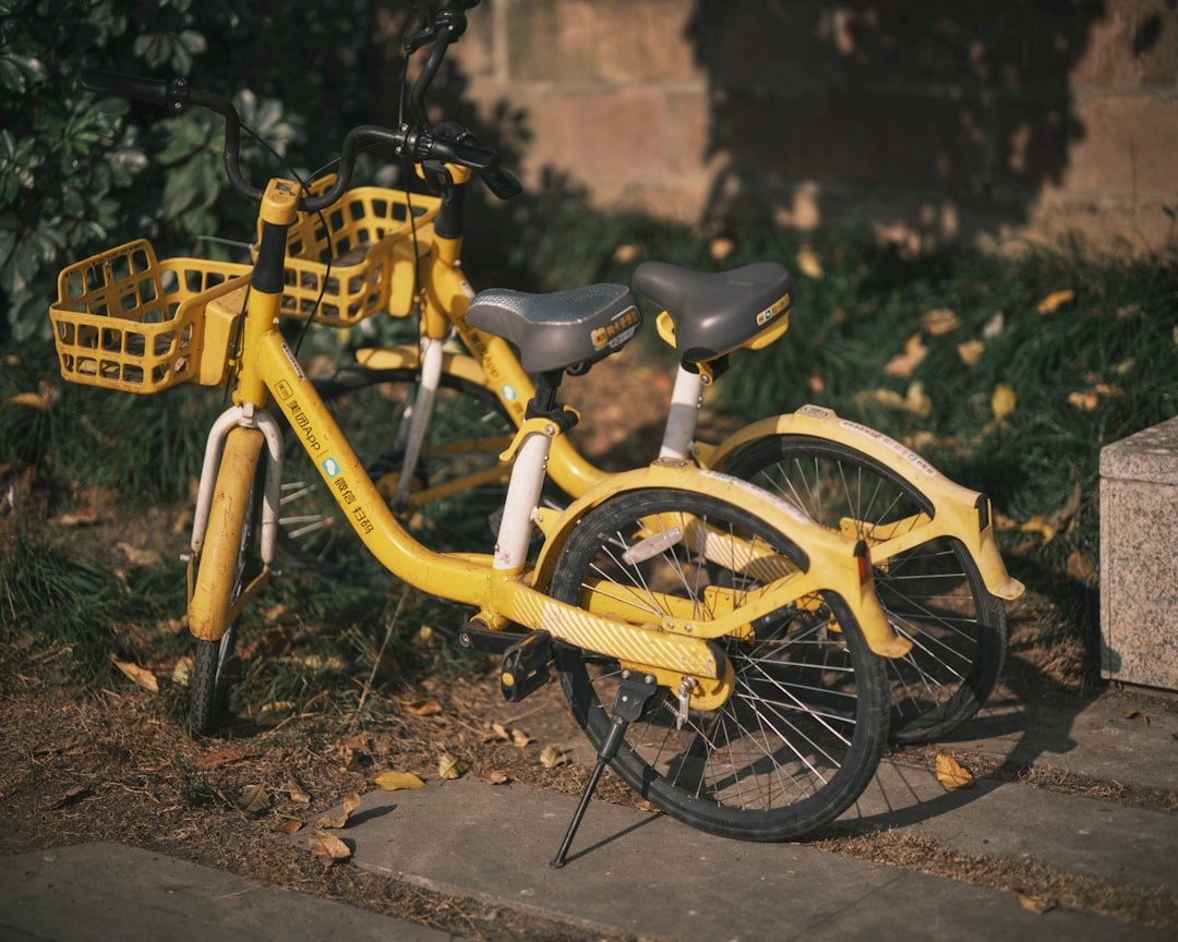 Two yellow bicycles parked outdoors near grass