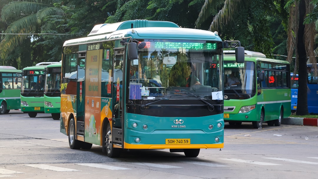 Green city buses lined up on a street.