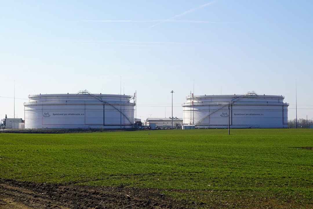 Two large white storage tanks in a field