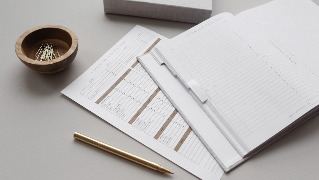 A finance tracker planner with budget sheets, a gold pen, and paper clips